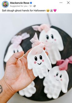 someone is holding up some fake ghost handprints on a cake with pink bows