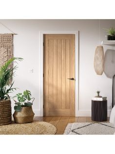 a room with a bed, rugs and plants on the floor next to a wooden door