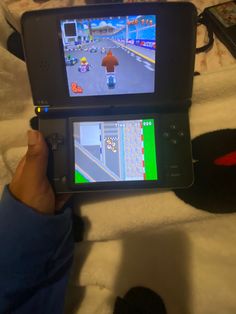 someone is holding up a game on their cell phone while playing mario kart in front of them