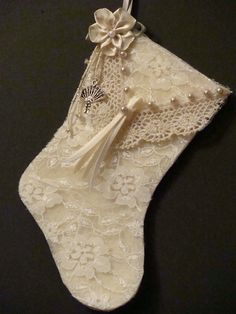 a white lace stocking hanging on a black wall with a ribbon and flower decoration