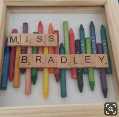 a wooden scrabble with crayons spelling the word'miss bradley '