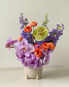 a white vase filled with lots of purple and orange flowers