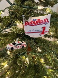 a car ornament hanging from the top of a christmas tree with baby ruth's 1 on it