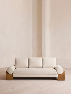 a white couch sitting on top of a hard wood floor next to a tall wall