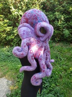 an octopus made out of yarn sitting on top of a wooden pole