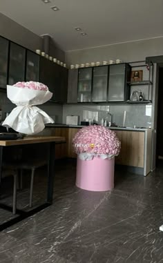 a large pink vase filled with flowers on top of a kitchen counter