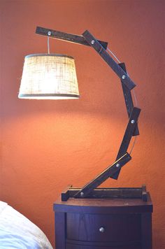 a lamp that is on top of a wooden table next to a wall with a light