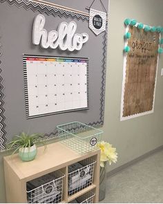 a wall with a calendar and some baskets on the floor in front of it that says hello