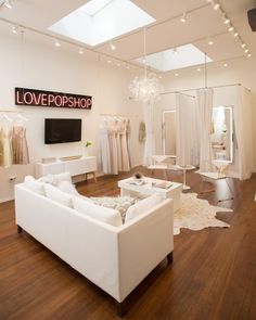 a living room filled with white furniture and lots of lights hanging from the ceiling above