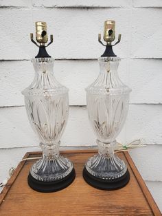 two clear glass vases sitting on top of a wooden table next to each other