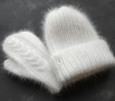 a pair of white knitted mittens sitting on top of a table