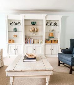 a living room with two chairs and a coffee table in front of bookshelves