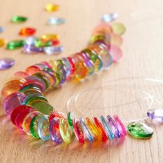 a necklace made out of glass beads on a wooden table with other items around it