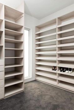 an empty walk in closet filled with lots of white shelves and shoes on top of them