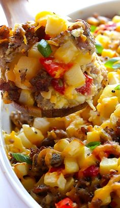 a spoon full of food that is being lifted from a casserole dish with meat and vegetables