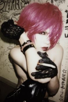 a woman with pink hair and black gloves