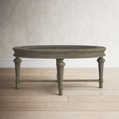 an oval coffee table with wooden legs and a glass top, on a hard wood floor