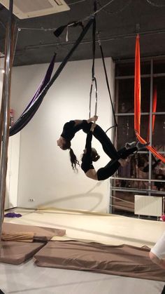 two people doing aerial acrobatics in an art gallery