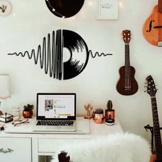 a laptop computer sitting on top of a desk next to guitars and other musical instruments