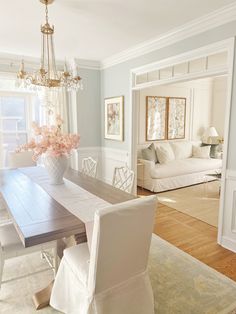 a dining room table with white chairs and a chandelier