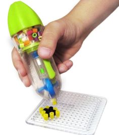 a child's hand is holding a green and yellow toy with lots of beads in it