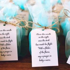 small favors with tags on them are sitting on a wooden table in front of blue organine bags