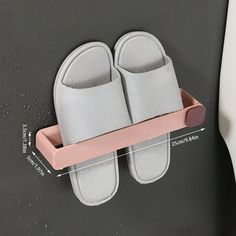 a pair of white slippers hanging from a hook on a gray wall with pink trim