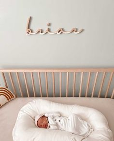 a baby is laying in a bed with the name birth on the wall above it