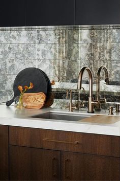 a kitchen sink sitting under a faucet next to a wooden cutting board on top of a counter