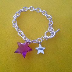 a silver bracelet with a purple star charm and a small pink crystal star on it