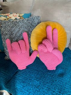 two pink gloves sitting on top of a blue blanket next to pillows and a yellow pillow