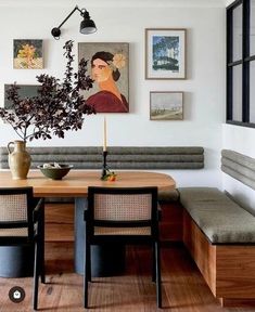 a table with two chairs and a bench in front of some pictures on the wall