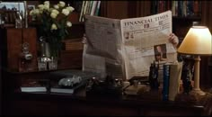 a person sitting at a desk with a newspaper in front of them and a lamp on top of it