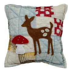 a decorative pillow with a deer and mushroom on the front, sitting on a white surface