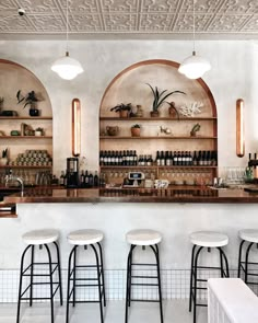 the bar has several stools and shelves with bottles on them in front of it