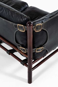 a black leather chair sitting on top of a wooden frame with two straps around it