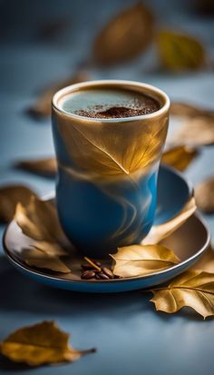 a cup of coffee sitting on top of a saucer next to some golden leaves