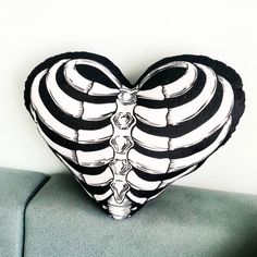 a black and white heart shaped pillow sitting on top of a green couch next to a wall