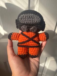 a small crocheted toy in the shape of a man wearing an orange and black outfit