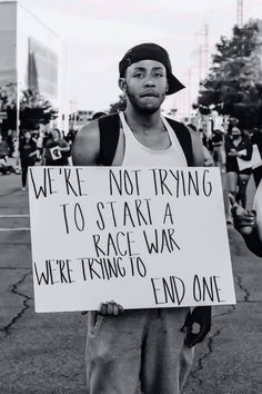 a man holding a sign that reads we're not trying to start a race, we're trying to end one