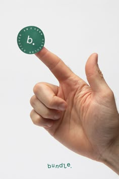 a hand is holding up a green sticker with the letter b on it's side