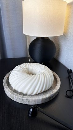 a white candle sitting on top of a table next to a black lamp