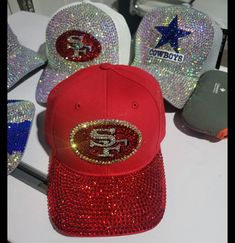 several hats with sequins on them are sitting on a white table and one is red