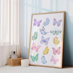 a frame with watercolor butterflies on it next to a basket and window sill