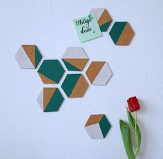 three pieces of paper are arranged on the wall with a tulip next to them