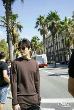 a man standing on the side of a street with palm trees in front of him