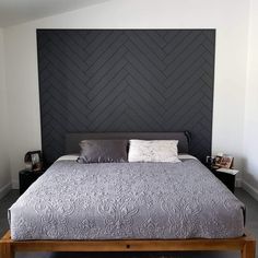 a large bed sitting in the middle of a bedroom next to a wall mounted headboard