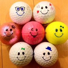 six golf balls with faces drawn on them in different colors and sizes, arranged in a pyramid