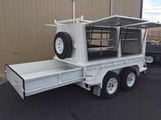 a white trailer parked in front of a building with wheels on it's sides