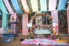 a bench with flowers and flamingos on it in front of an outdoor ceremony area